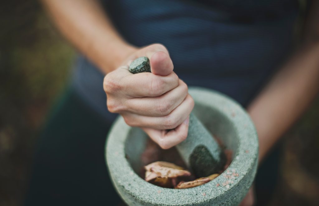 A woman grinds powder in a mortar and pestle