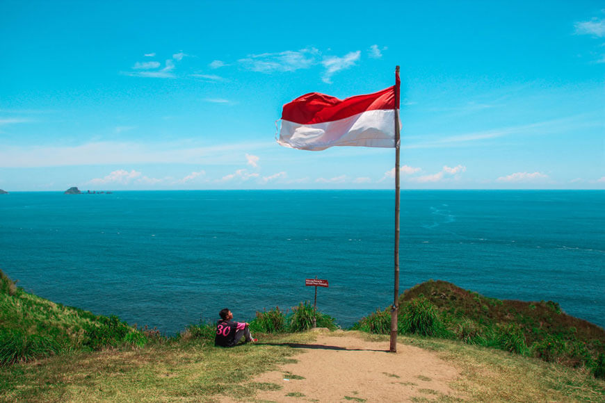 Person sitting beneath the flag of Indonesia