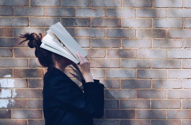 Woman-holds-books-to-her-face-in-frustration