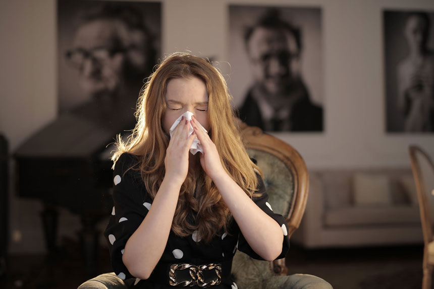 A woman sneezes into a kleenex
