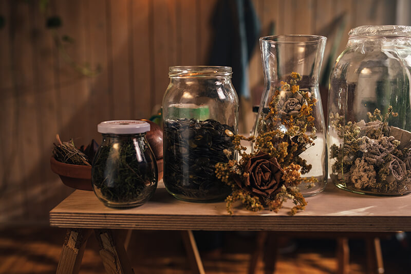 Glass jars of botanicals on a wood table