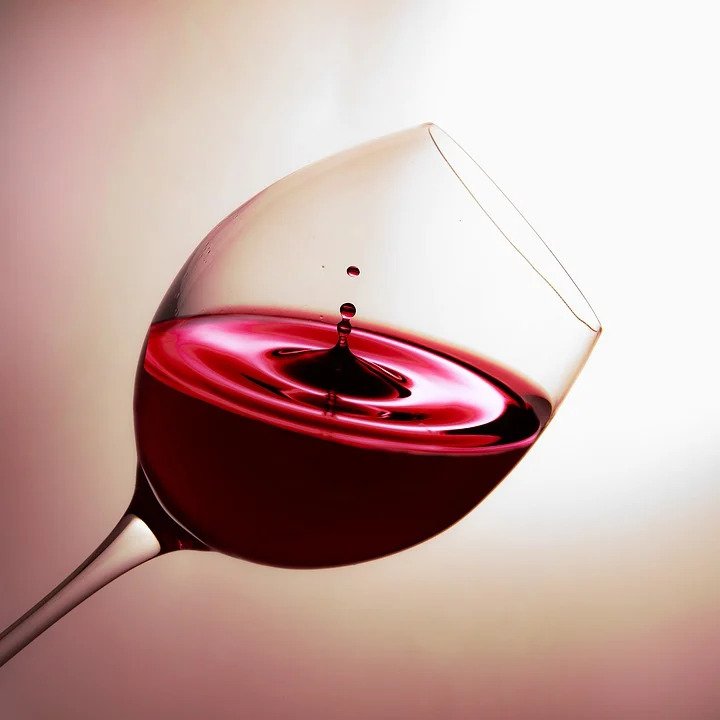 A glass of red wine held on a slant.