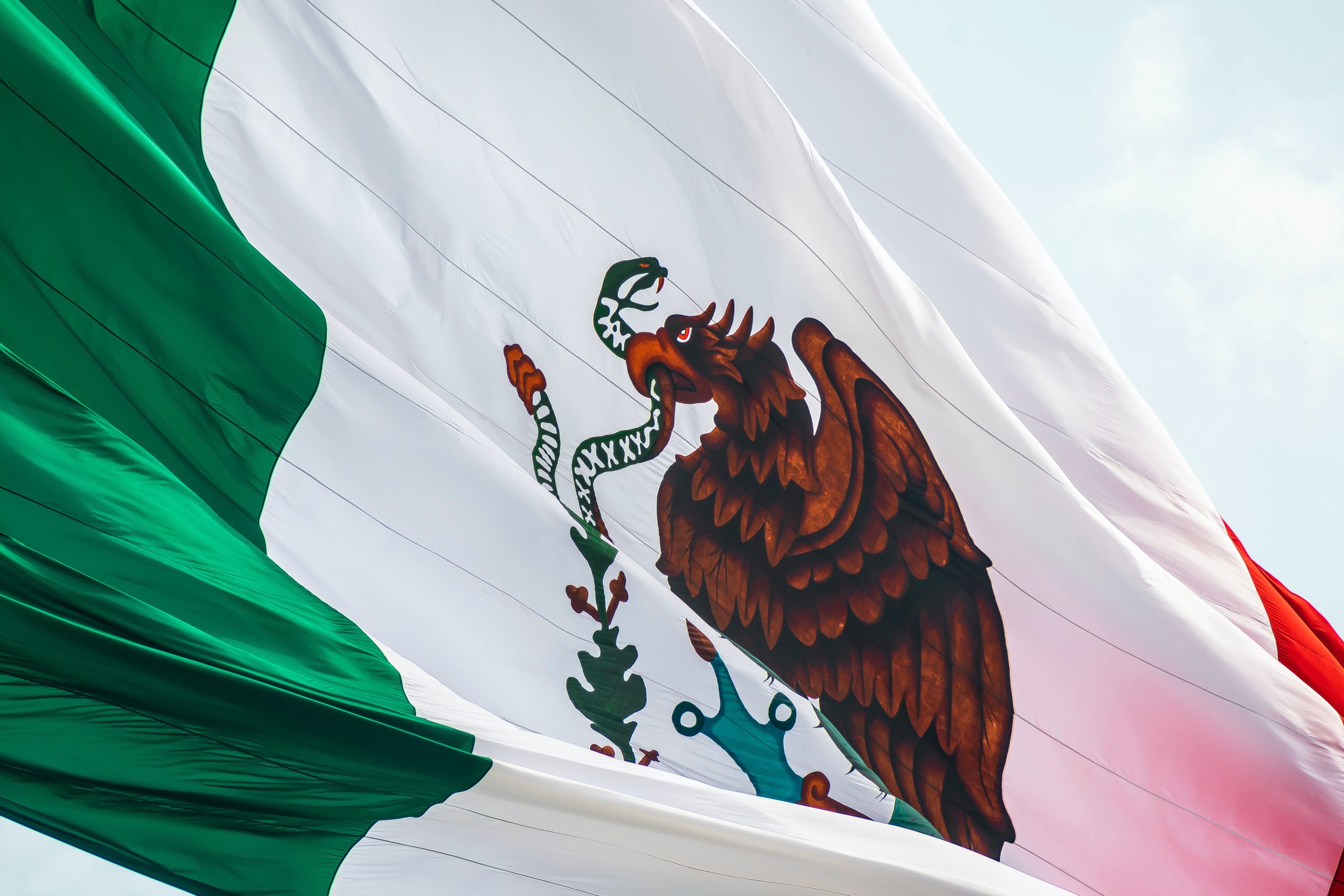Red, white, and green Mexico flag against a blue sky