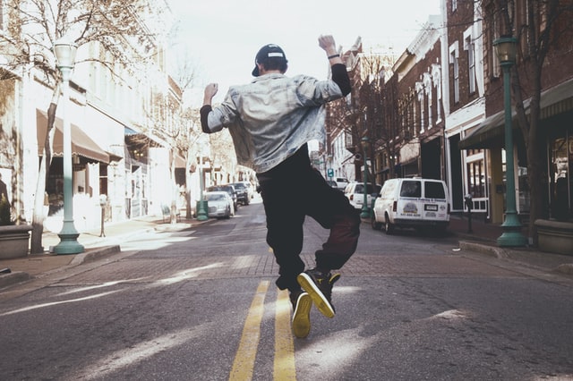 Man jumps for joy in the middle of a city street.