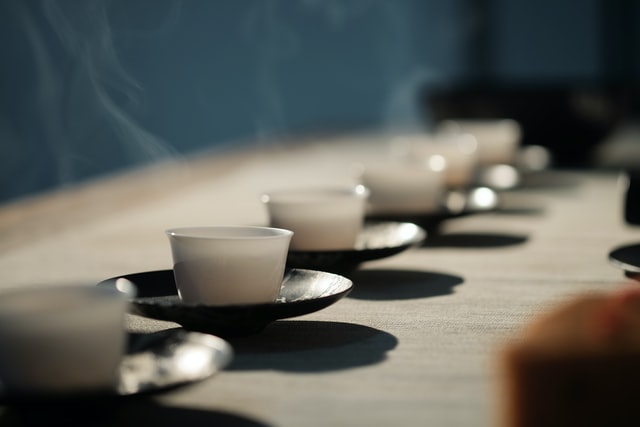 Steaming white teacups arranged in a row on a wooden table