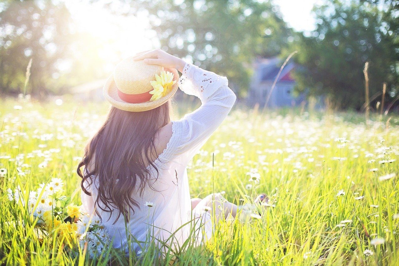 A woman outdoors in a meadow following health and wellness tips.